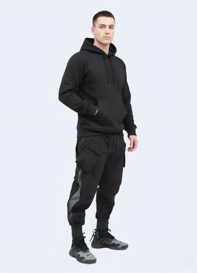 Side view of man dressed in black techwear jogger pants and hoodie, showing pocket details and modern streetwear silhouette.