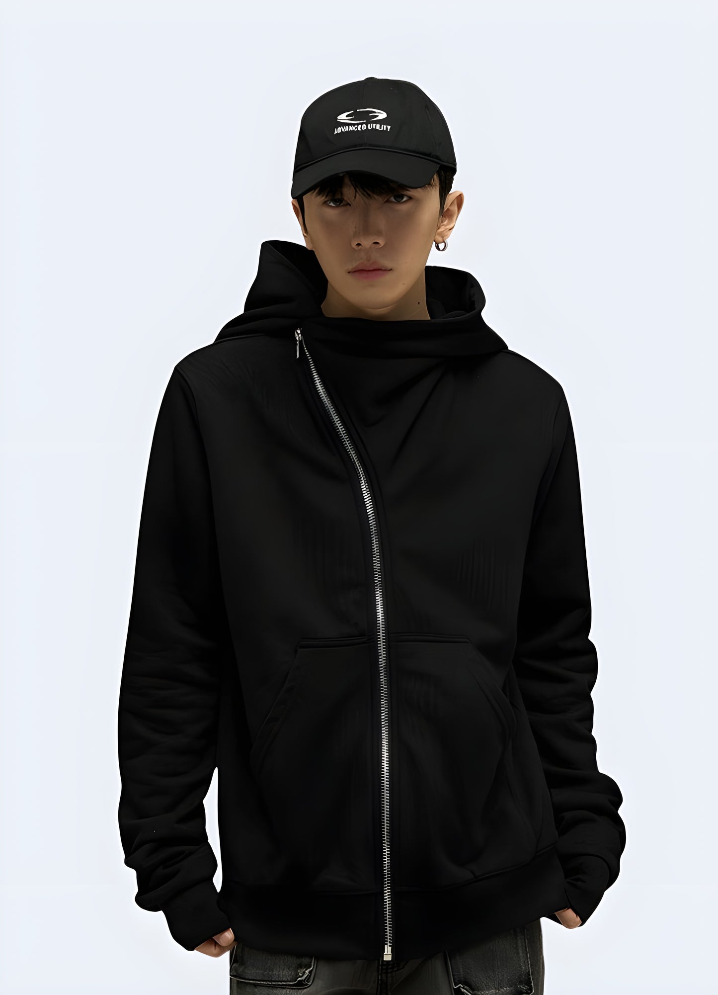 Front view of a person wearing a black zip-up hoodie with a white skull and crossed swords design, standing in a dark urban setting.