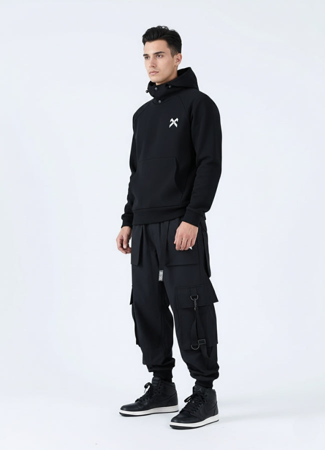 Person wearing a black hoodie and cargo pants with a white logo on a white background