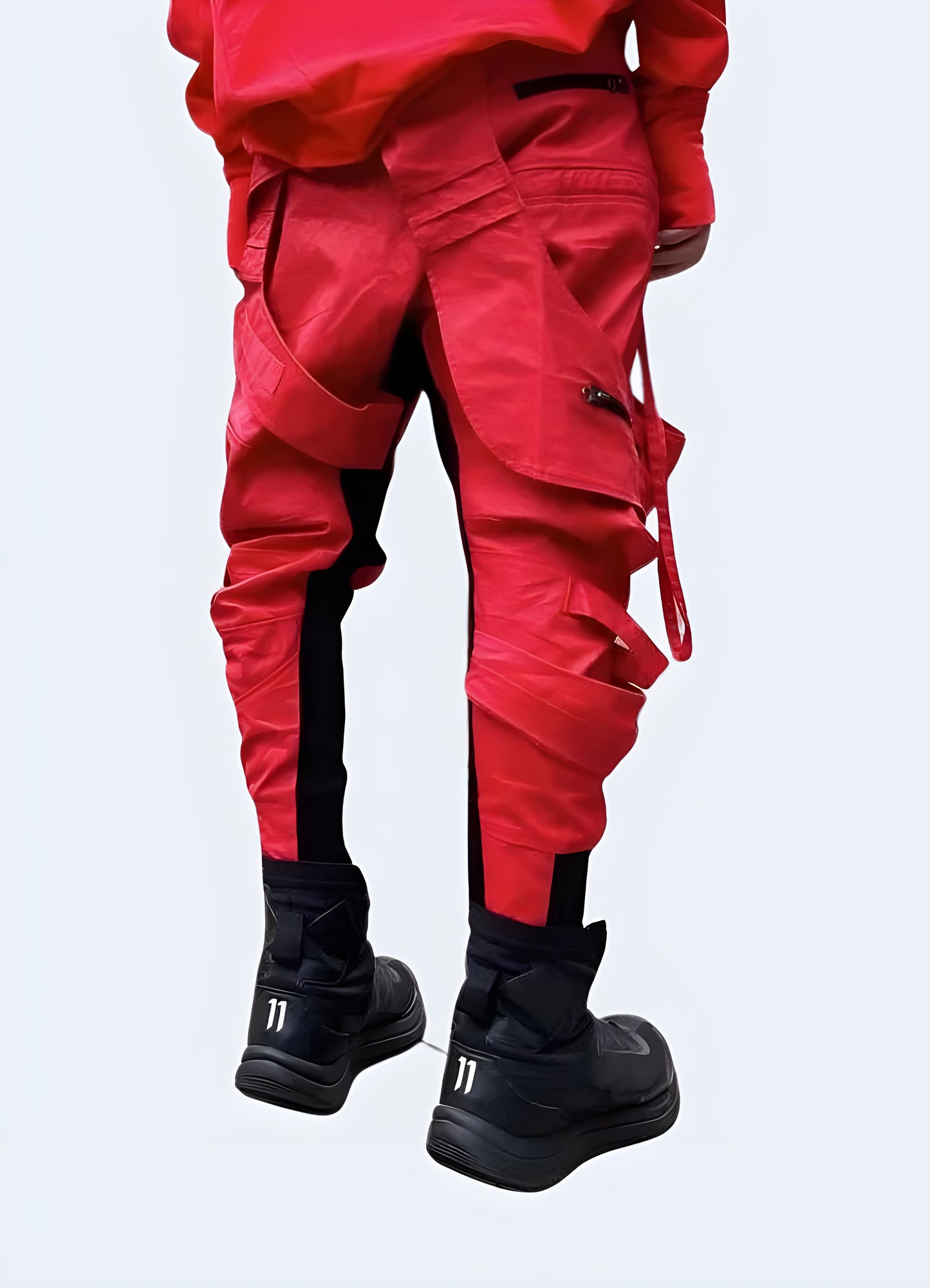 Back view of a man wearing striking asymmetric waxed red techwear pants, showcasing their unconventional design and high-quality craftsmanship for fashion enthusiasts in Canada.