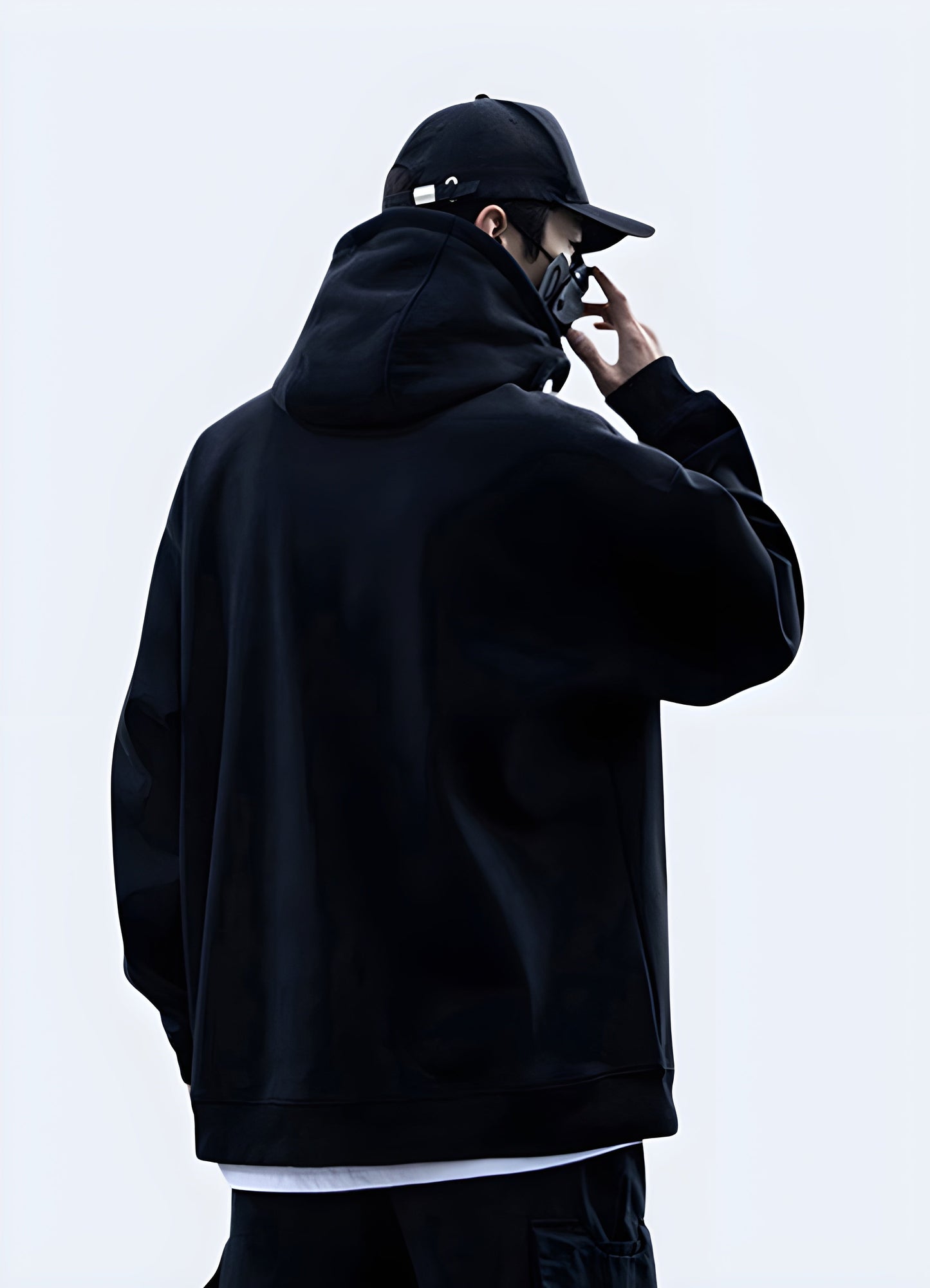Back and side view of a man wearing a sleek black techwear goth hoodie in the Canada, showcasing its unique design.