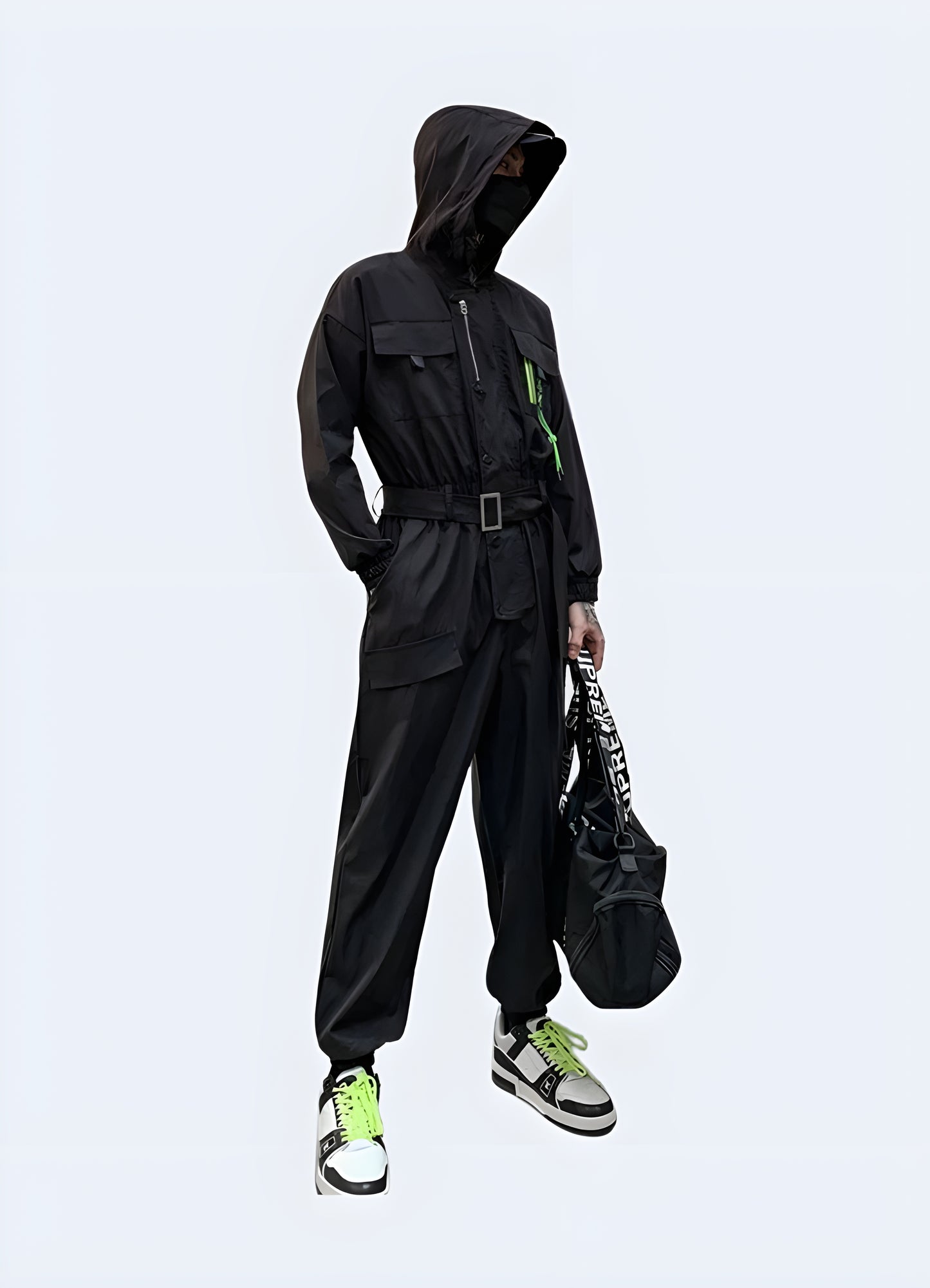 Side view of a man wearing a stylish black techwear jumpsuit with multiple pockets and straps, standing on a city street in Canada.