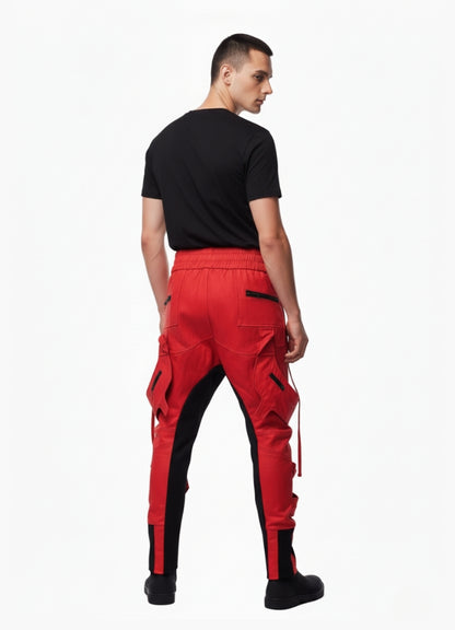 Rear view of man wearing red and black cyberpunk cargo pants with zipper pockets and tapered fit, styled with black t-shirt.