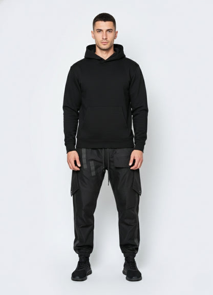 Front view of man dressed in cyberpunk pants showcasing tactical streetwear design on plain white background.