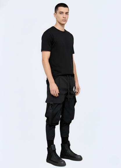 Side angle of black tactical techwear pants showcasing strap details, reinforced knees, and urban utility design.