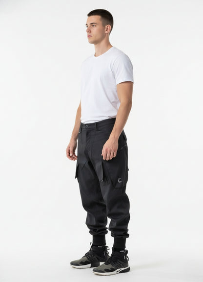 Side angle of black futuristic cargo pants showcasing pocket structure, articulated knees, and modern urban fit.