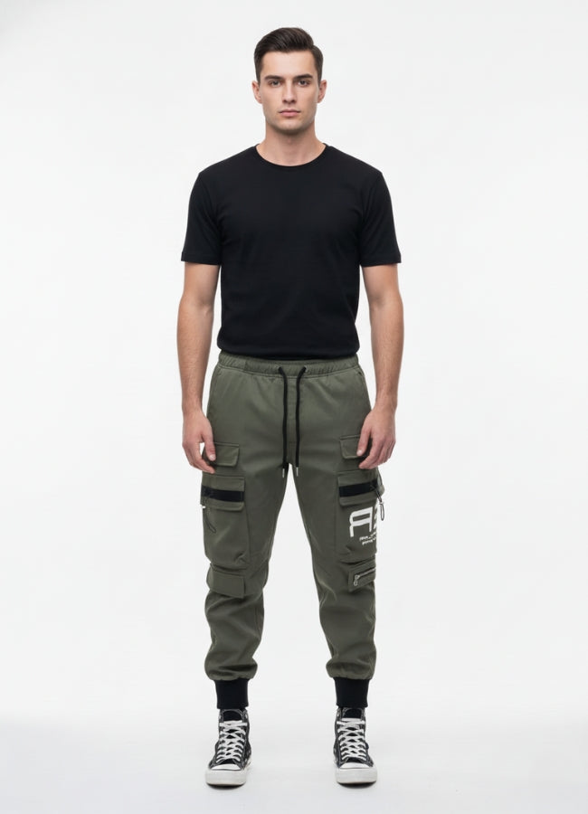 Front view of a man wearing khaki techwear cargo pants with multiple pockets and black detailing, paired with a black T-shirt and black high-top sneakers