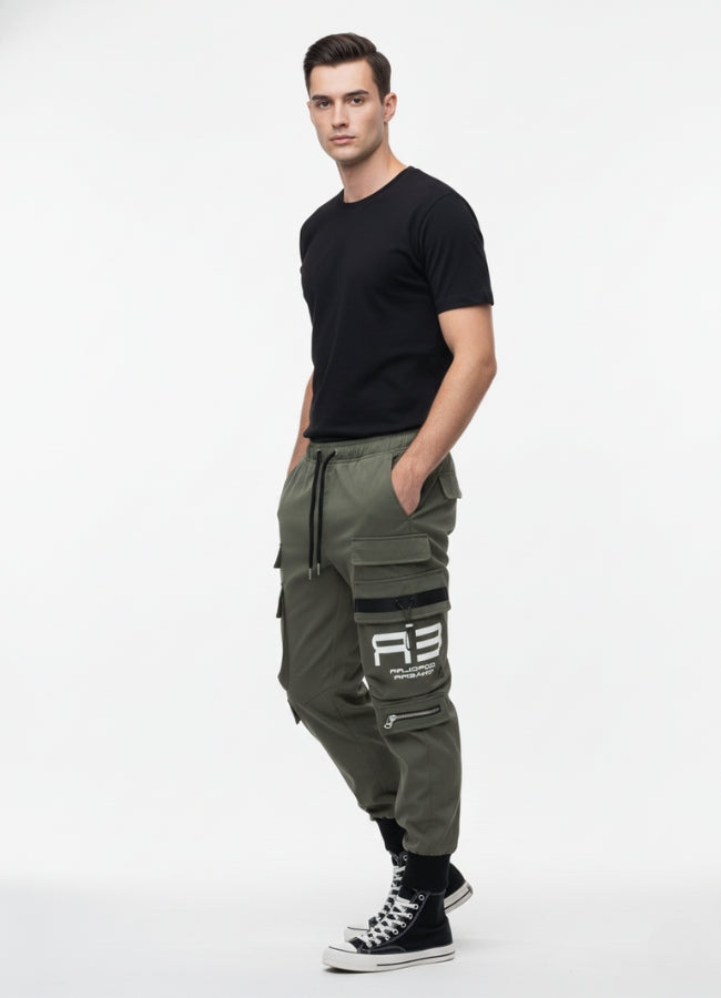 Side view of a man wearing khaki techwear cargo pants with multiple pockets and black detailing, paired with a black T-shirt and black high-top sneakers.