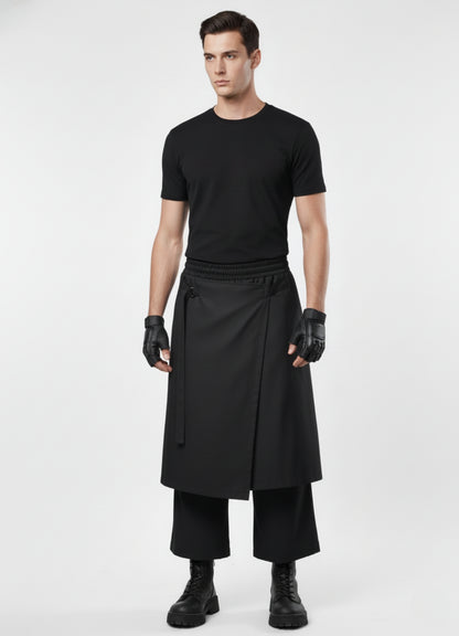 Male model wearing black wrap techwear skirt over wide-leg pants, styled with fitted black tee, gloves, and combat boots.