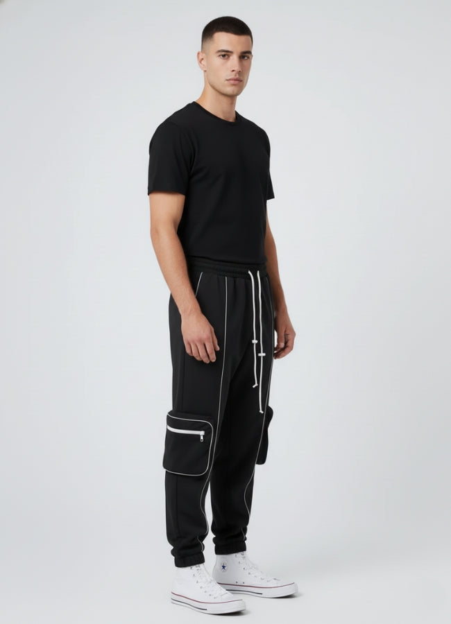 Side angle of black techwear pants featuring reflective seams, cargo pockets, and modern tapered fit.