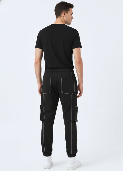 Rear view of black techwear pants highlighting reflective stitching, elastic waistband, and dual patch pockets.