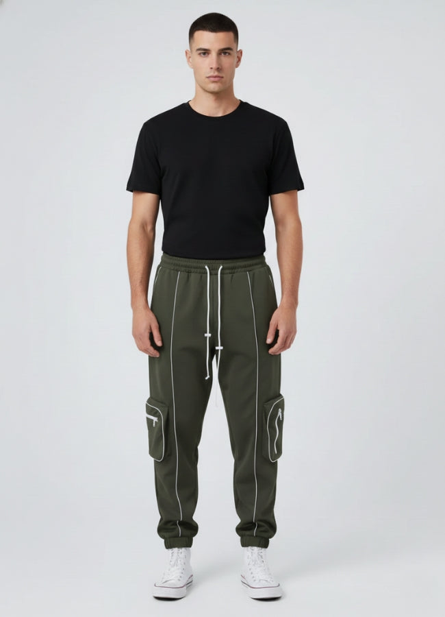 Male model wearing olive green techwear jogger pants with white reflective and side cargo pockets, paired with black tee and white sneakers.