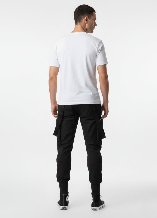 Rear view of techwear cropped pants with utility pockets and strap accents, styled with white tee and black high-top sneakers