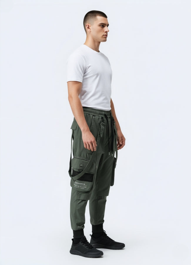 Side angle of green techwear cropped pants highlighting multi-pocket design, straps, and modern urban fit.