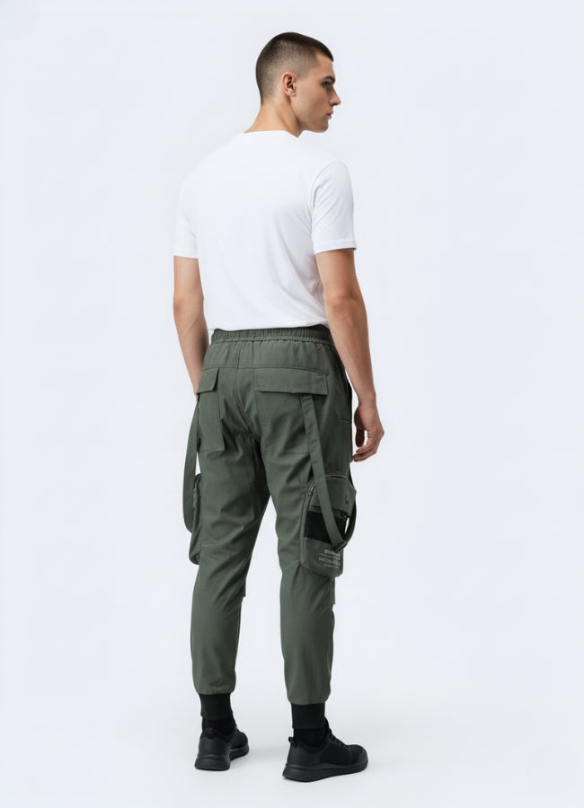 Rear view of green techwear cropped pants featuring pockets, strap details, and elastic cuffs, paired with minimalist white tee