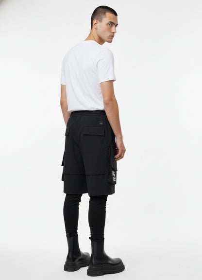 Rear view of black techwear leggings short with utility straps and back pockets, paired with black boots.