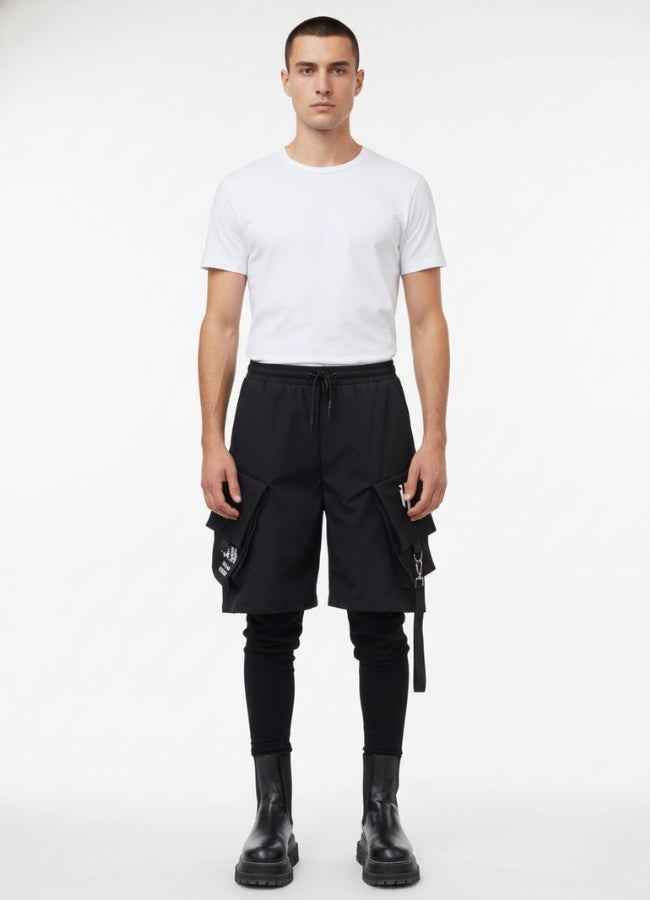 Male model wearing techwear leggings short pants, featuring oversized flap pockets and drawstring waist.