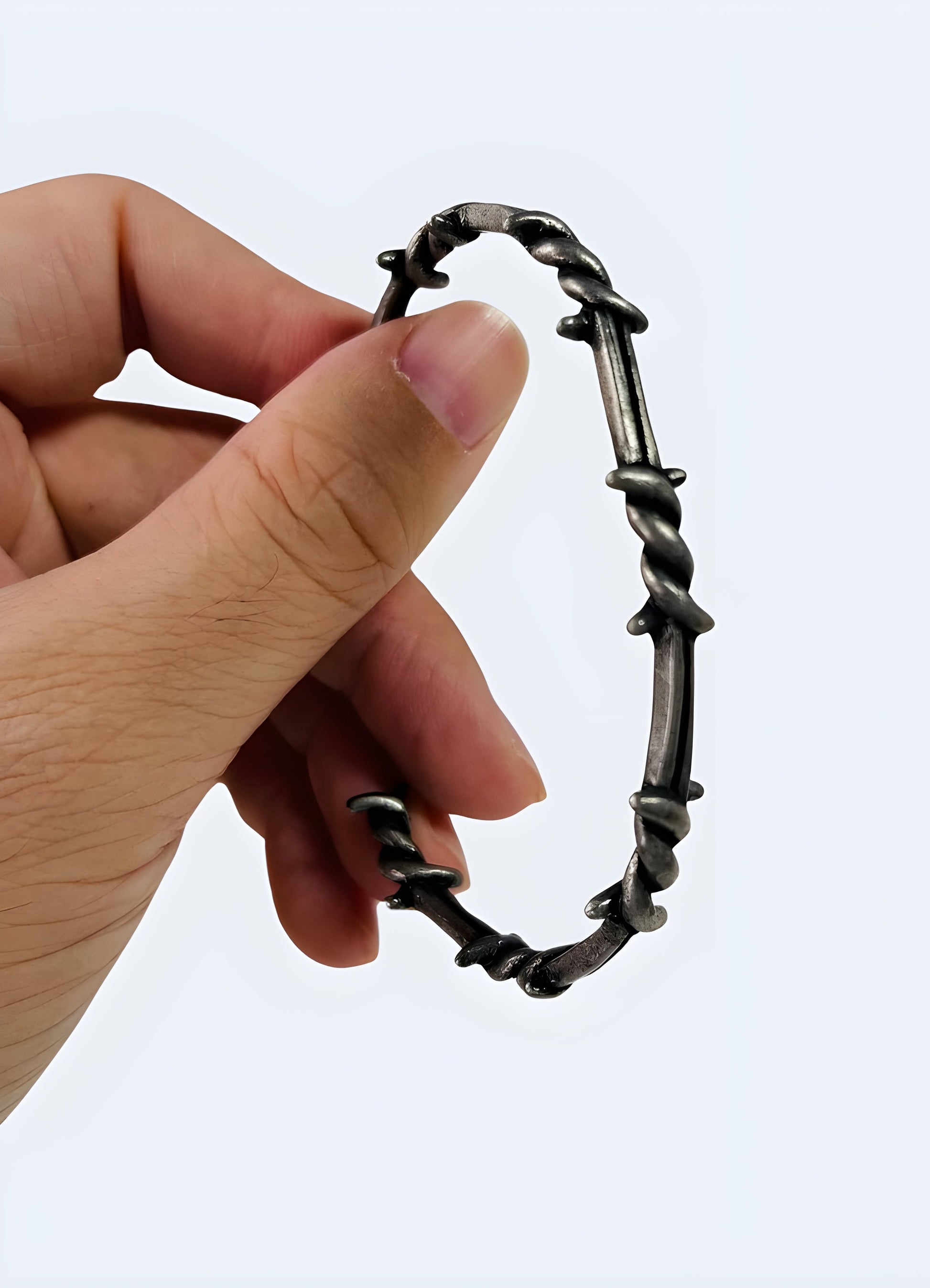 Barbed wire bangle displayed from the side view, showcasing its intricate barbed wire pattern and sleek metallic finish Canada.