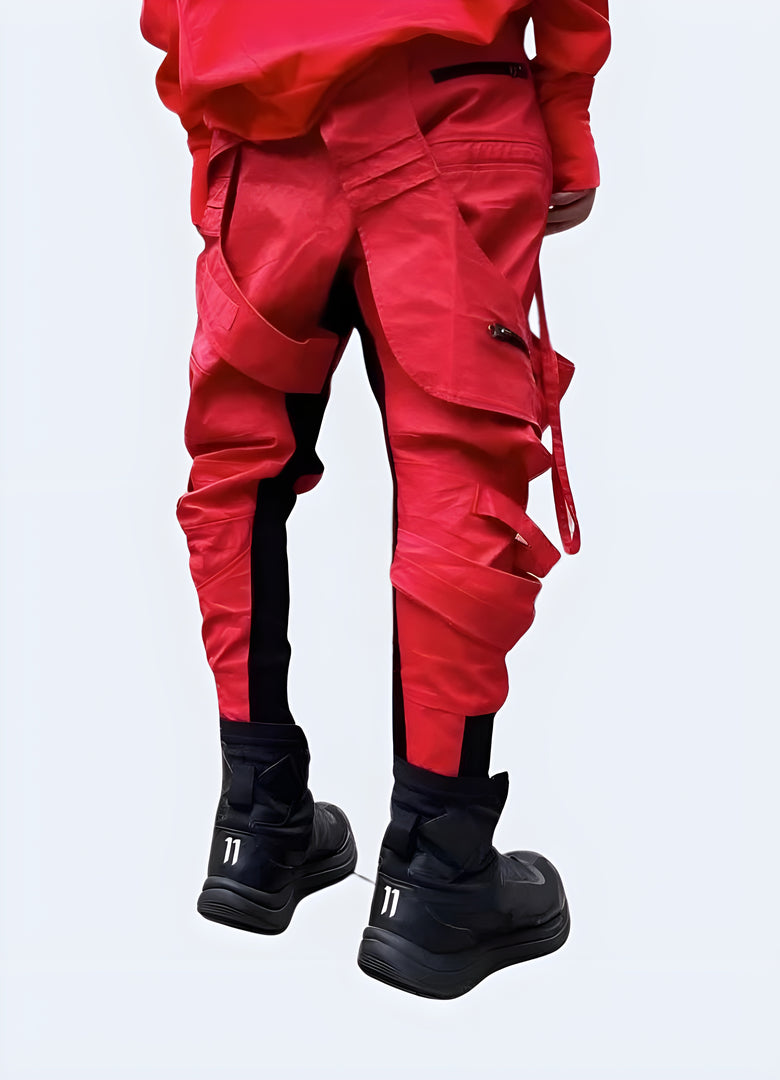 Back view of a man wearing striking asymmetric waxed red techwear pants, showcasing their unconventional design and high-quality craftsmanship for fashion enthusiasts in Canada.