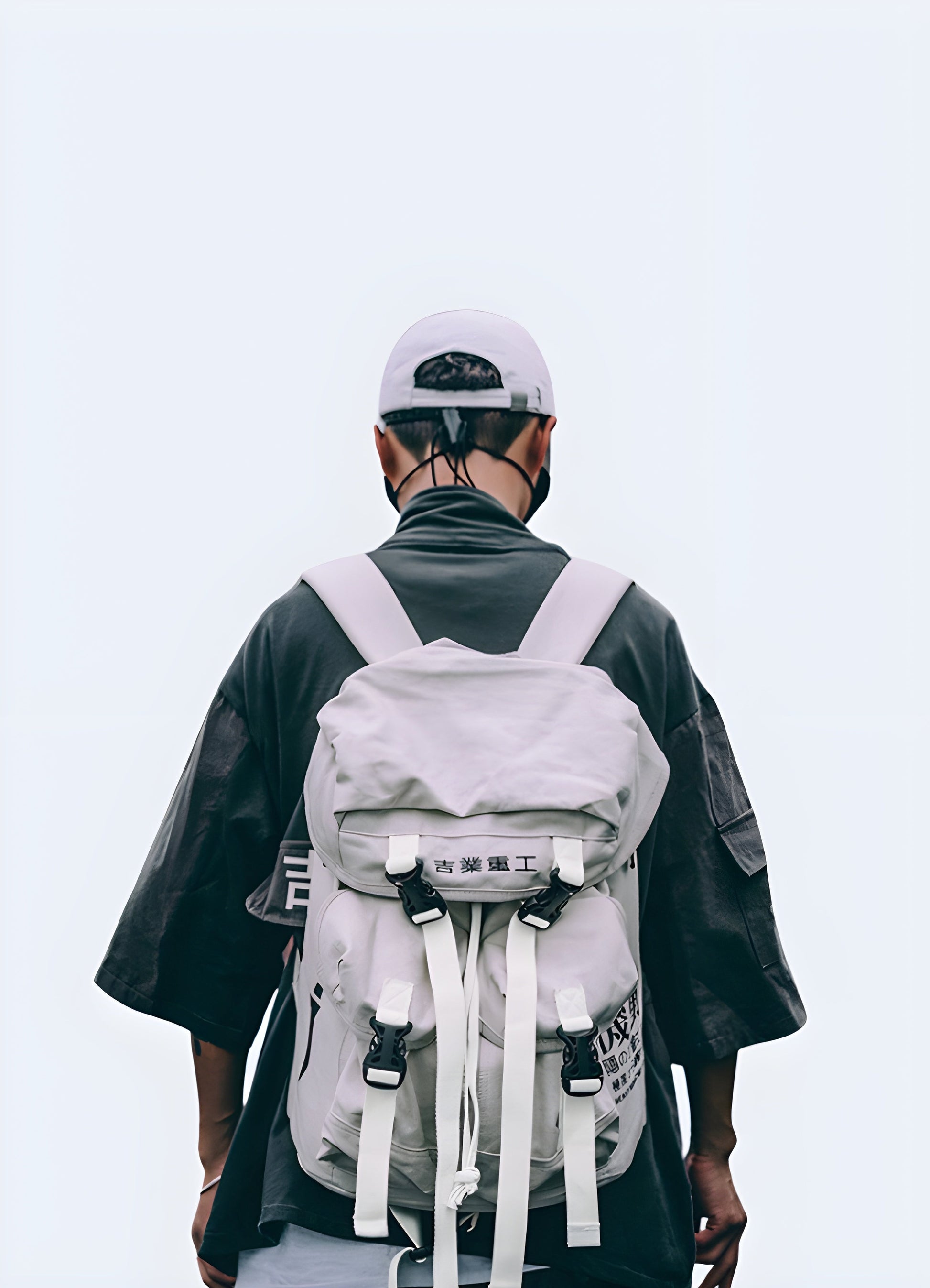 A man wearing a Japanese streetwear-style backpack in white, viewed from the front. The backpack features a clean, minimalist design Canada with subtle detailing.