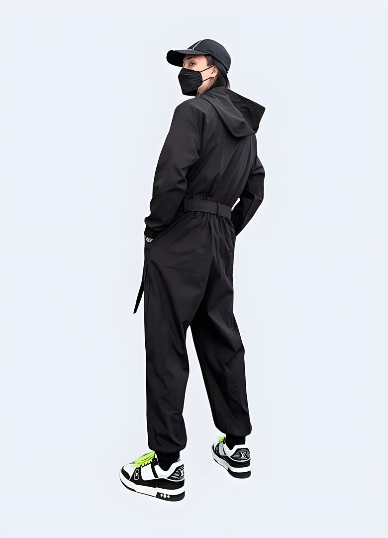 Back view of a man modeling a cutting-edge black techwear jumpsuit with multiple pockets and a hood, perfect for urban exploration and fashion-forward style in the Canada.