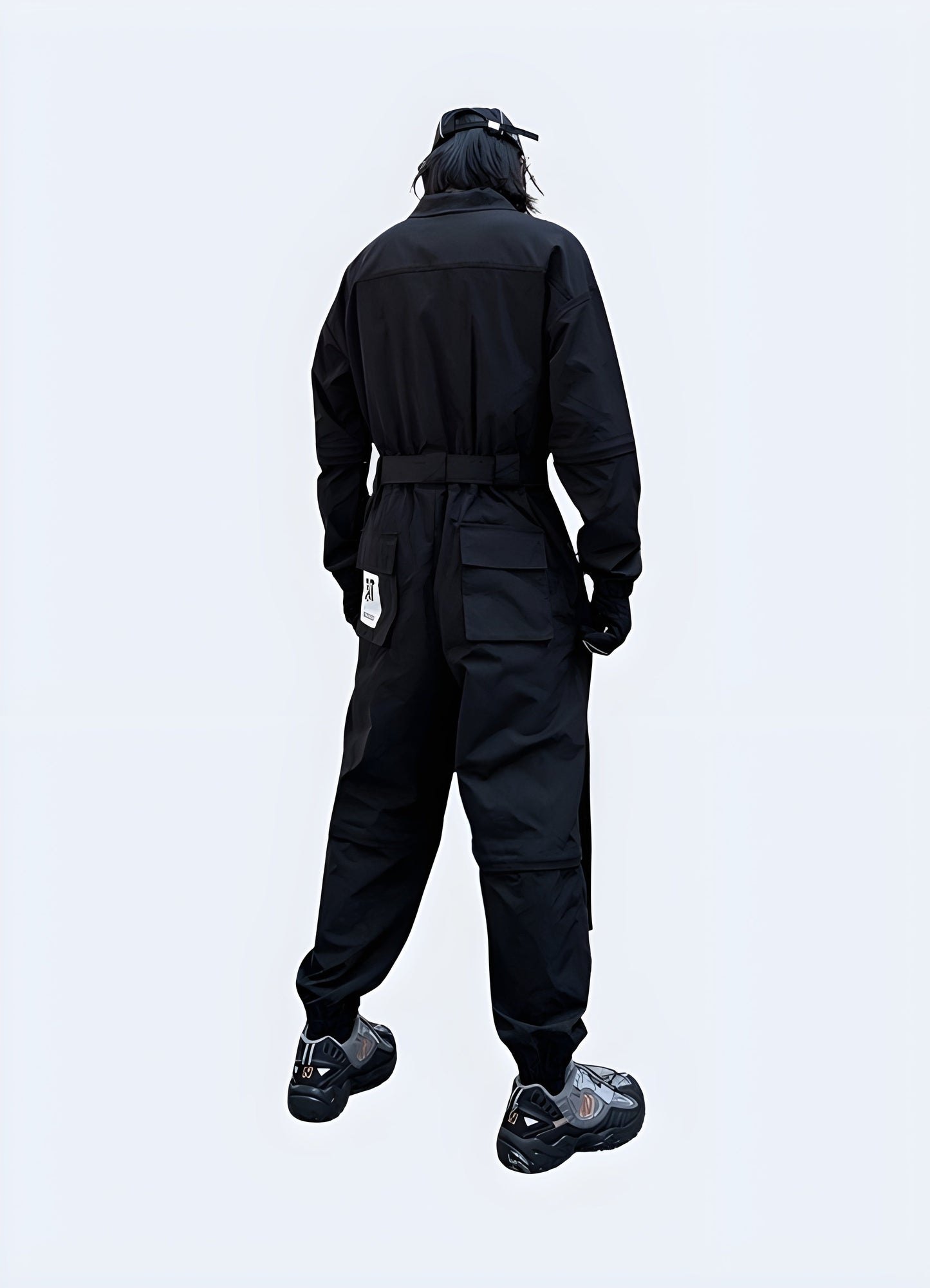 Back view of a man wearing innovative black techwear workwear featuring cargo pockets and straps, standing on a city street in Canada.