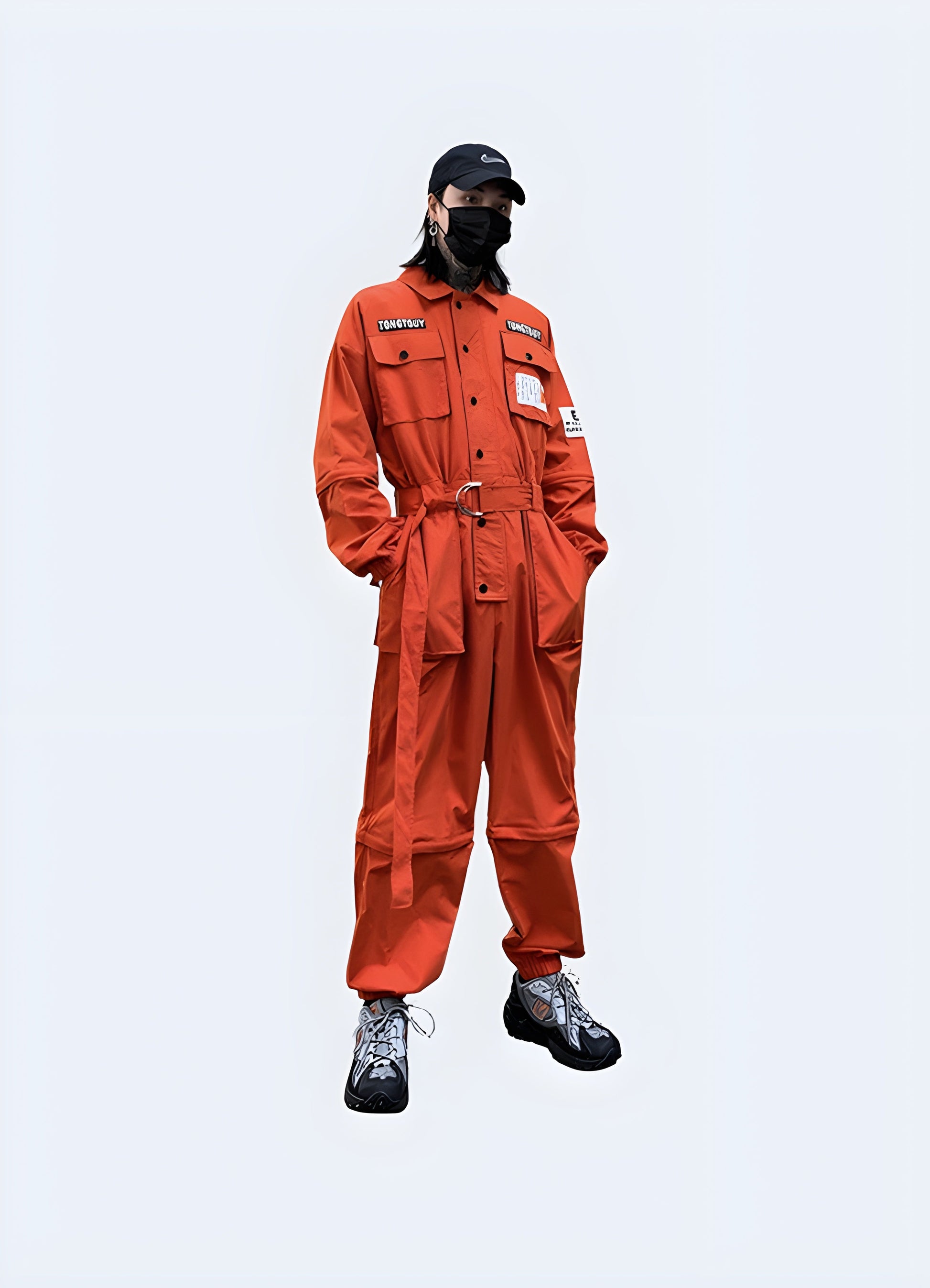 Front view of a man in a stylish orange techwear workwear outfit with numerous pockets and straps, posing in an urban Canadian environment.