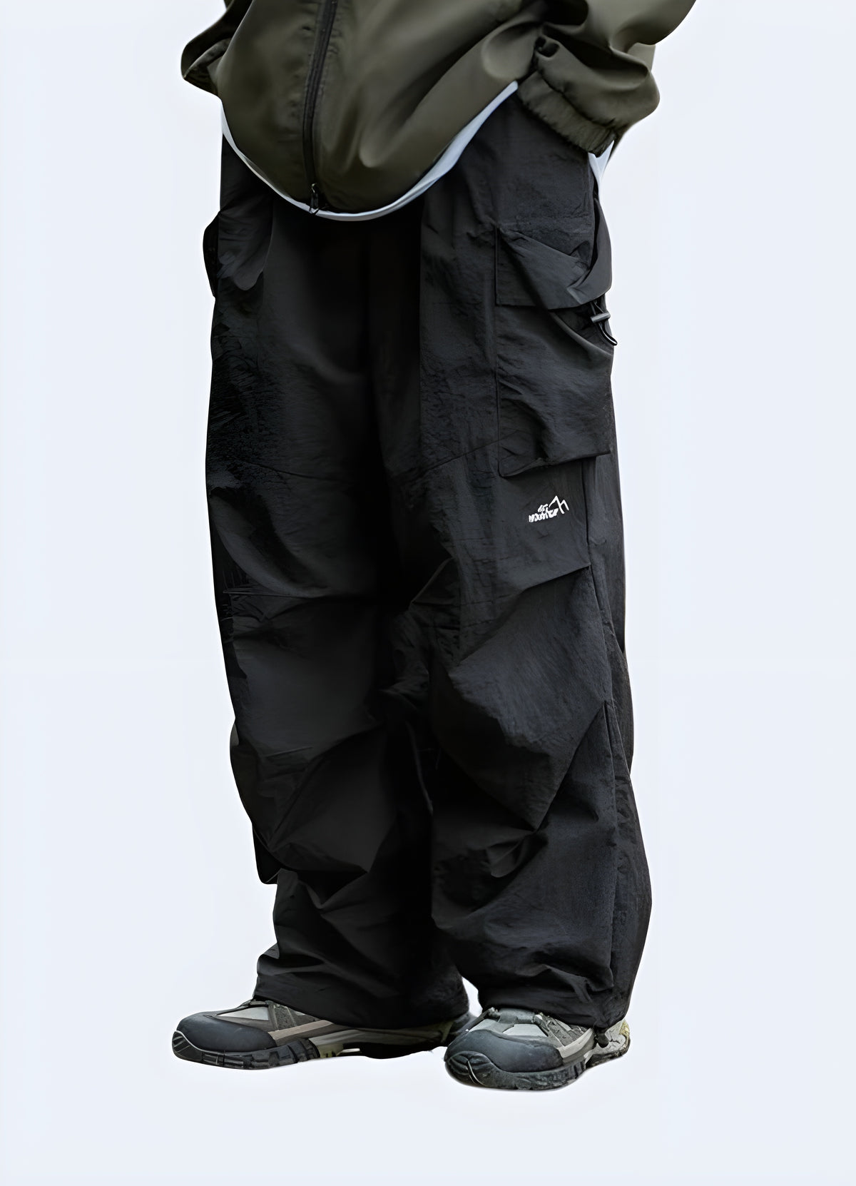 Black streetwear parachute pants for men, detail of the oversized leg and hem