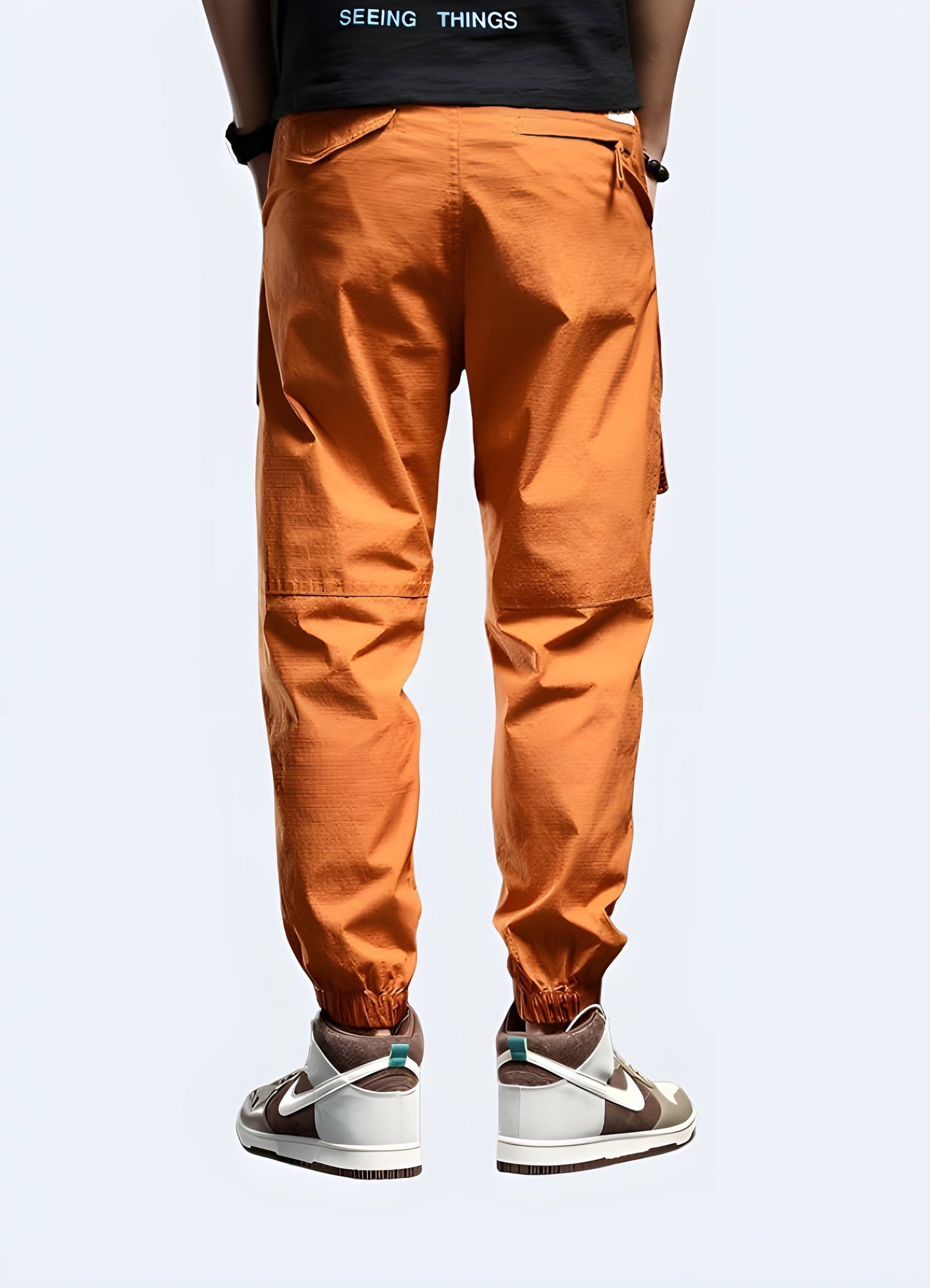 Men wearing eye-catching orange techwear pants, back view, showcasing the modern fit and technical features perfect for city life in Canada.