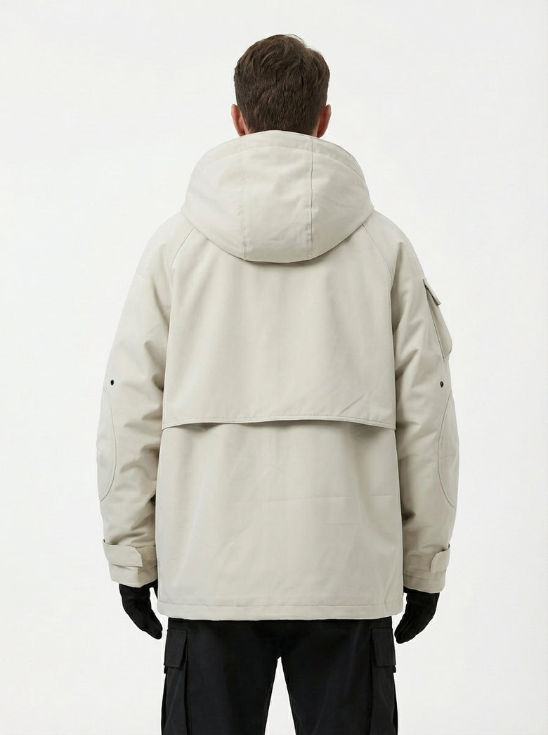 Rear view of the male model showing the back of the beige techwear jacket, featuring a large hood, a back yoke flap design, a sleeve pocket, and adjustable cuffs, paired with black cargo pants and gloves.