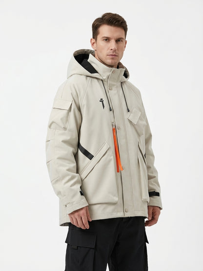 Front view of a Caucasian male model wearing a beige hooded techwear jacket with an orange zipper strap, black contrast tape details, and multiple cargo pockets, styled with black cargo pants against a white studio background.