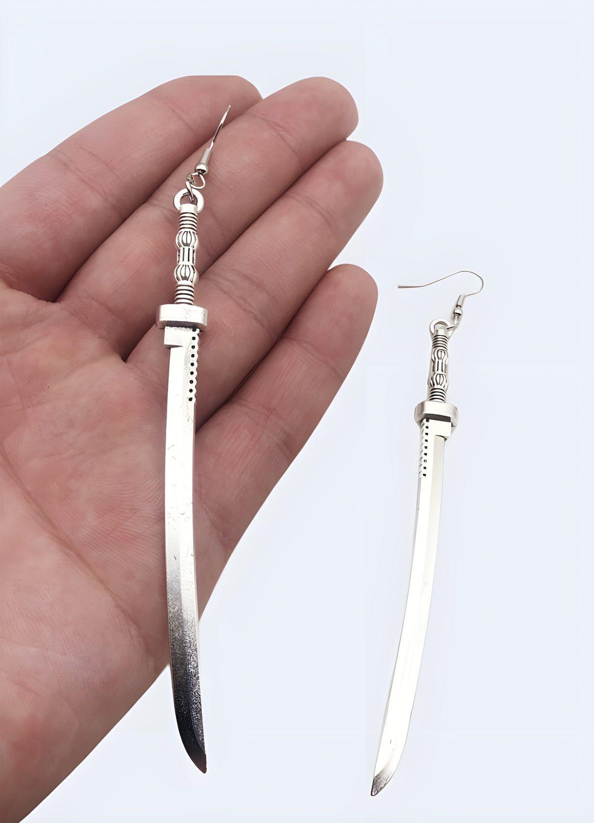 Sword Earrings laid flat, showing the silver-tone finish and full drop length