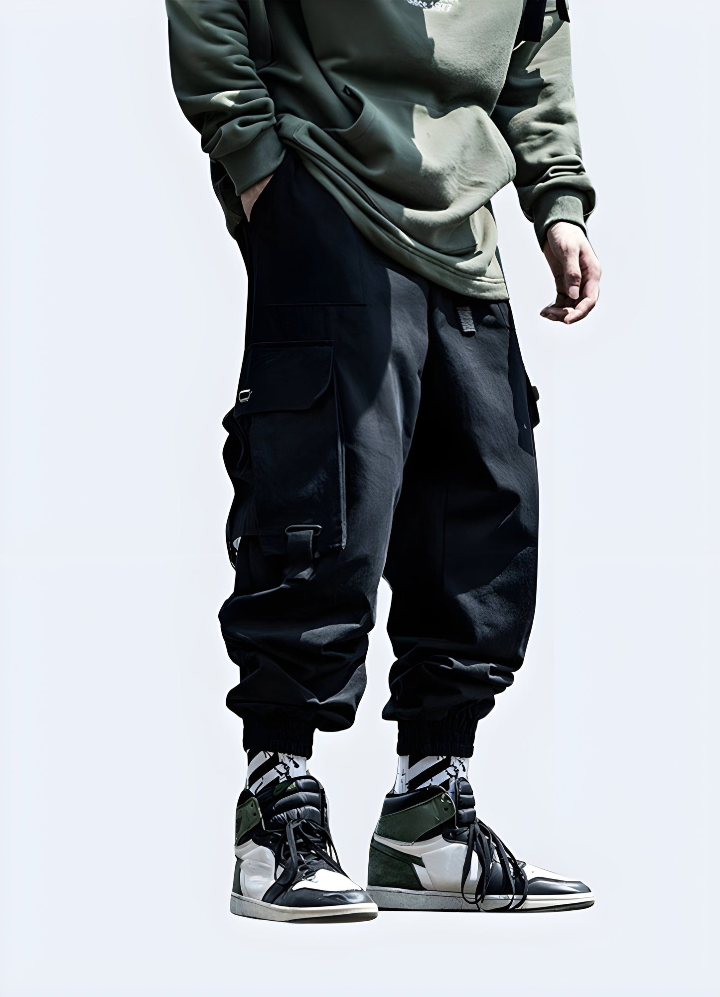 Model wearing black techwear cargo trousers with multiple pockets and straps, front view, canada fashion.