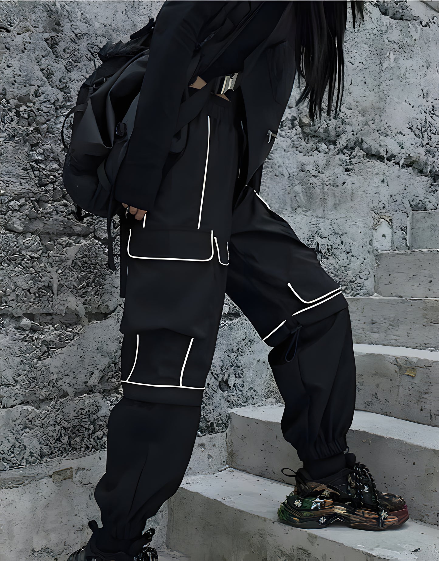 Side view of a woman wearing black reflective cargo pants, highlighting the techwear aesthetic and functionality for urban exploration in the Canada.