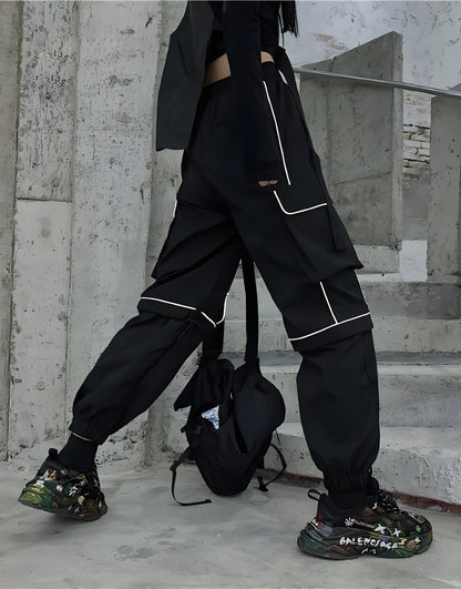 Model view of a woman wearing black reflective cargo pants, highlighting the techwear aesthetic and functionality for urban exploration in the Canada.