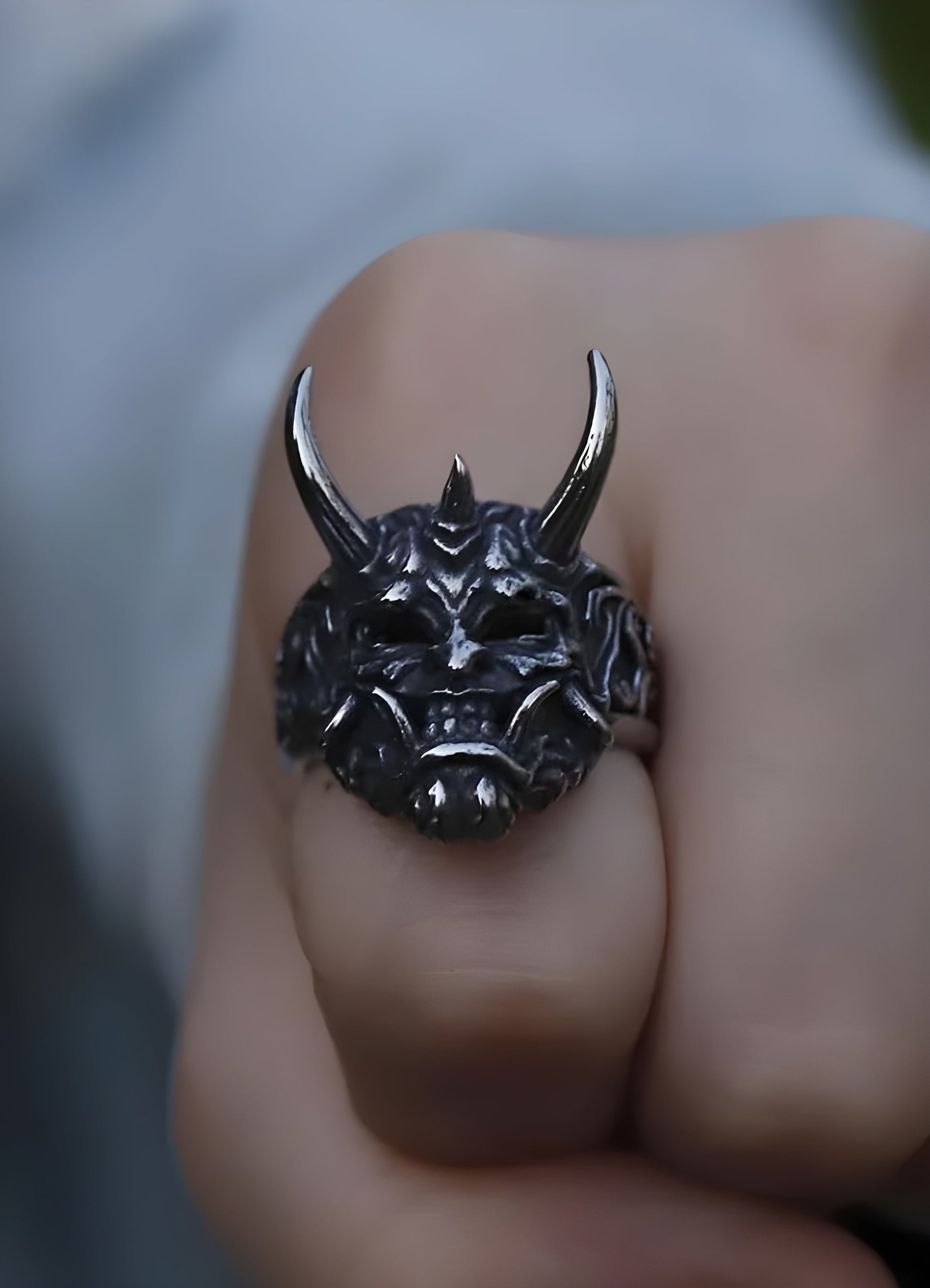 A model wearing an Oni ring, showing the front view of the ring with its intricate demon face design and metallic finish.