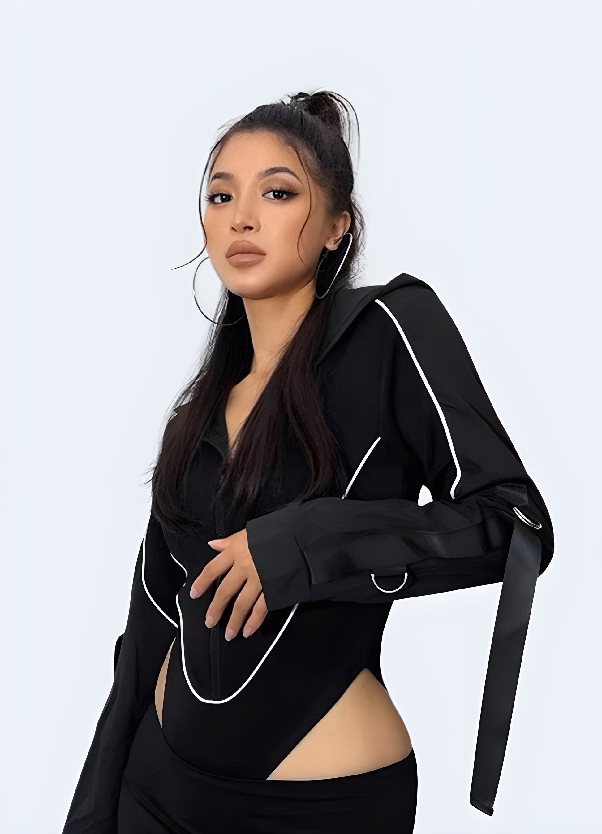 Front side view of a woman wearing a cutting-edge black hoodie bodysuit, demonstrating its modern aesthetic and functionality for Canada fashion-forward individuals.