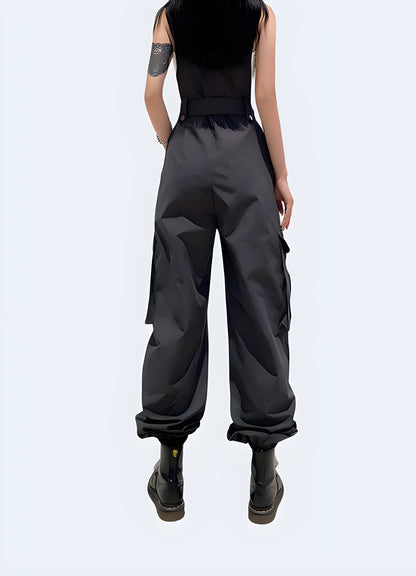 Back view of a woman in fashionable black techwear overalls with cargo pockets and straps, standing on a city street in Canada.