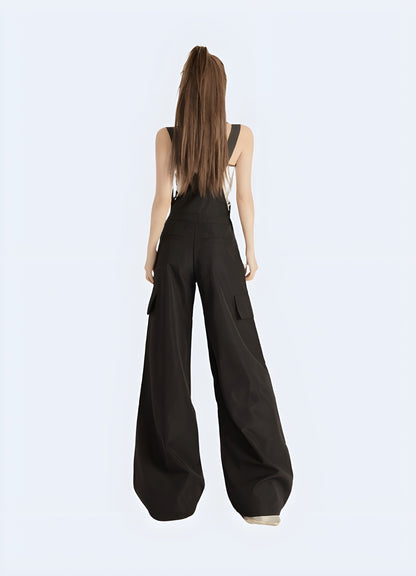 Back view of a woman in fashionable black techwear overalls with cargo pockets and straps, standing on a city street in Canada.