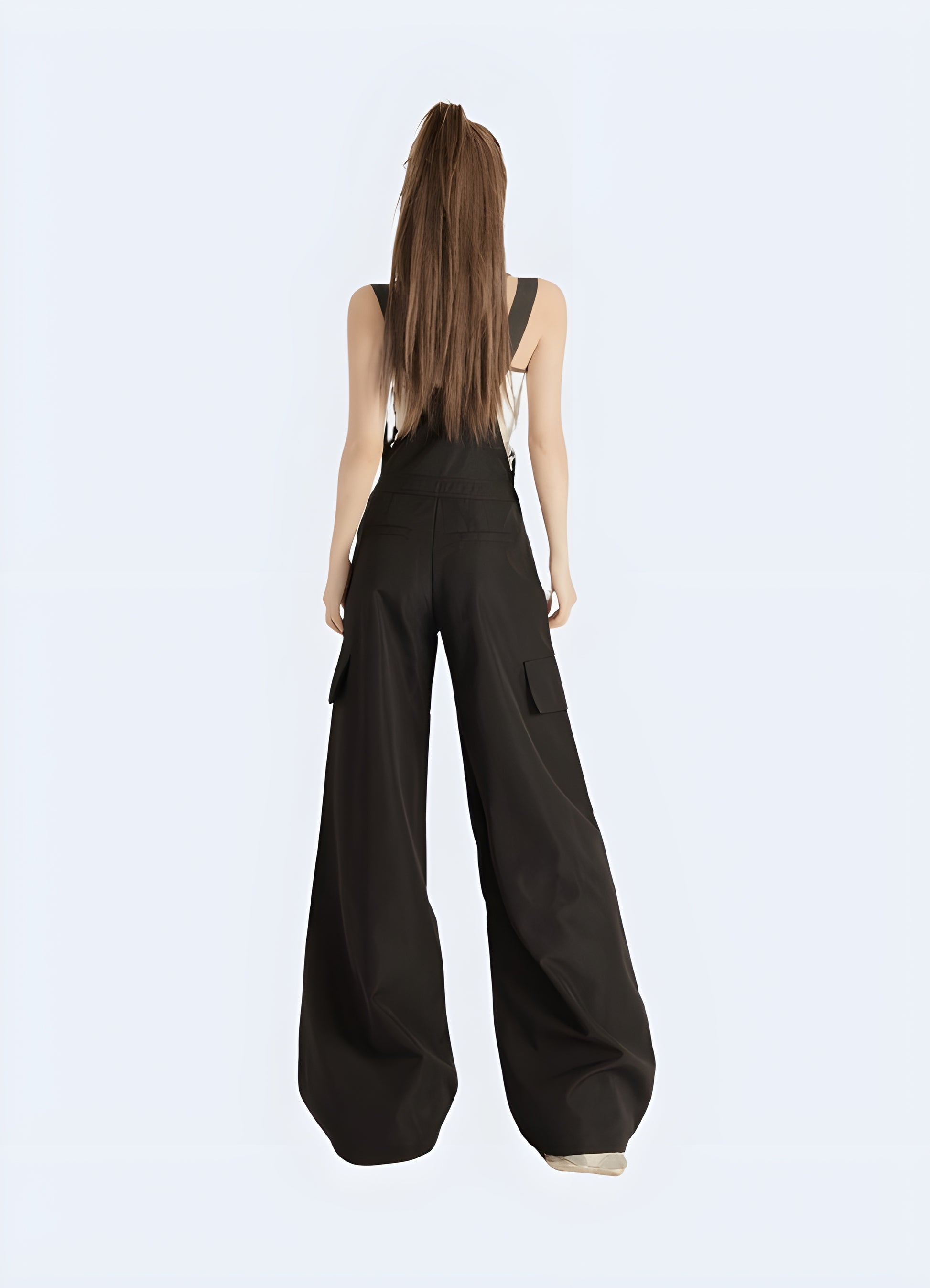 Back view of a woman in fashionable black techwear overalls with cargo pockets and straps, standing on a city street in Canada.