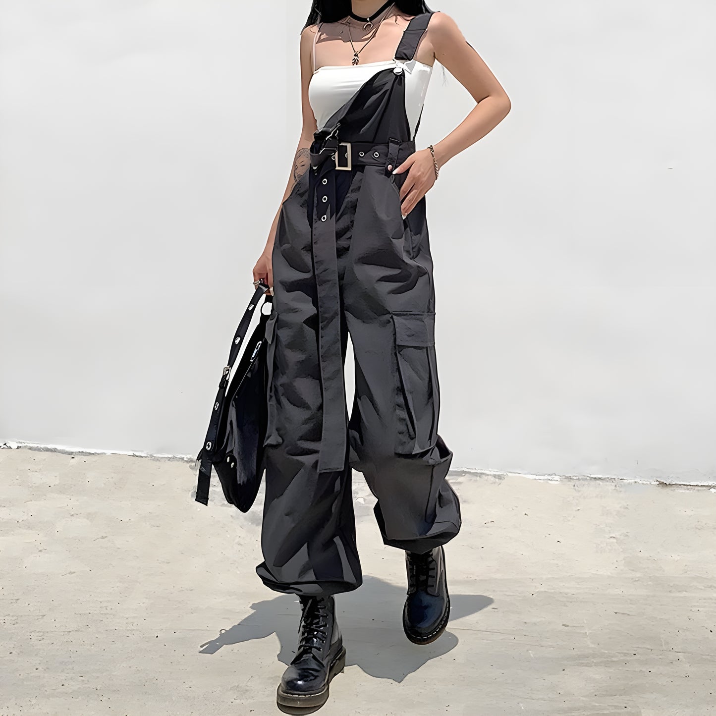 Model view of a woman in fashionable black techwear overalls with cargo pockets and straps, standing on a city street in Canada.