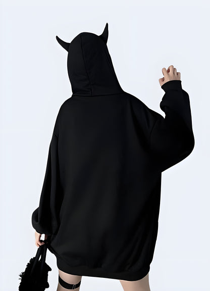 Woman wearing a women's techwear black hoodie with horns, showing a unique back view in a Canadian city.