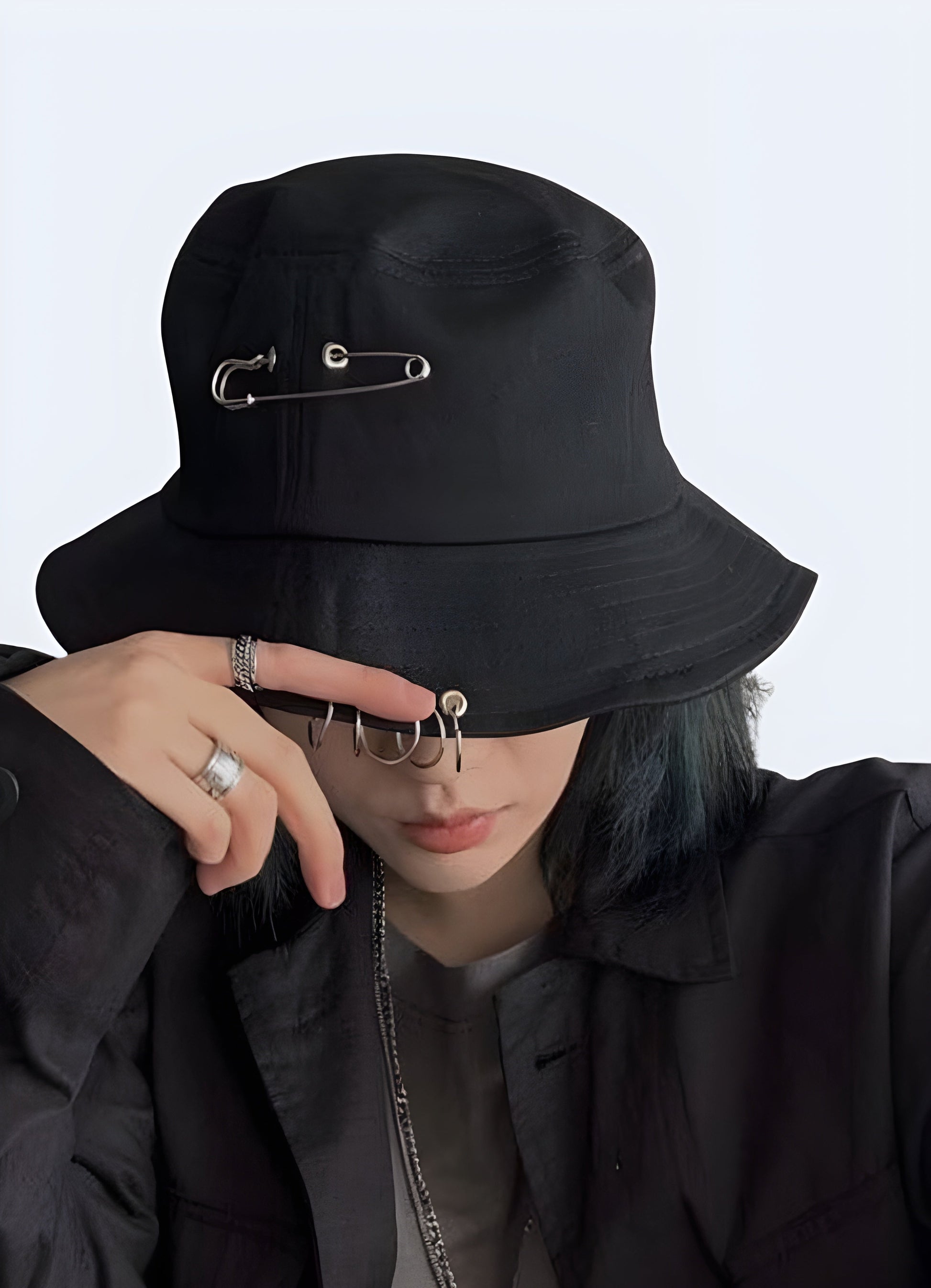 A woman wearing a black bucket hat adorned with metallic rings, shown from the front to highlight the hat's edgy design and how it complements her overall style.