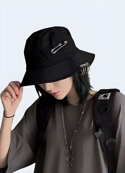 A woman wearing a black bucket hat adorned with metallic rings, shown from the side to highlight the hat's edgy design and how it complements her overall style.