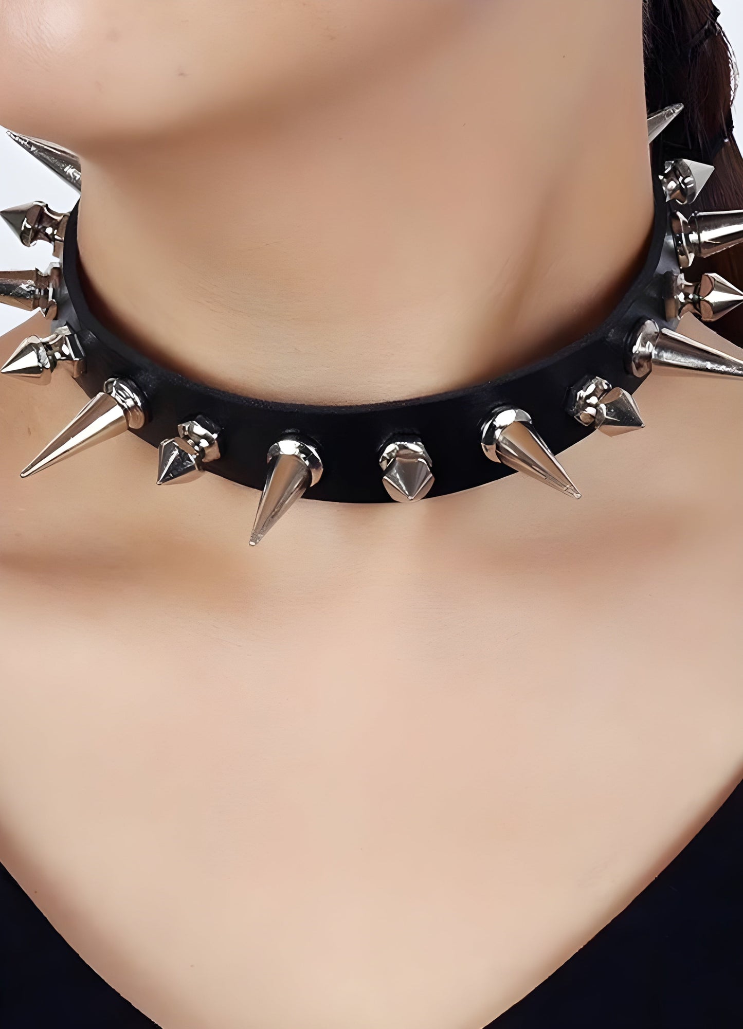 A woman confidently wearing a spike choker necklace, displayed from the front to highlight the necklace's sharp spikes and edgy style, set against a simple background to emphasize the overall look.