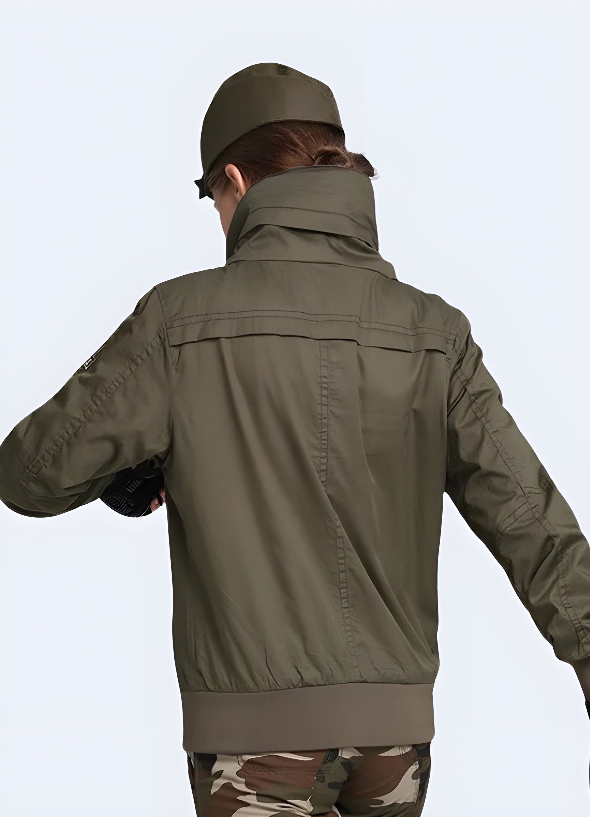 A back side view of a woman sporting a rugged and fashionable Canada-made techwear army bomber with hood women, highlighting the garment's superior construction and attention to detail.