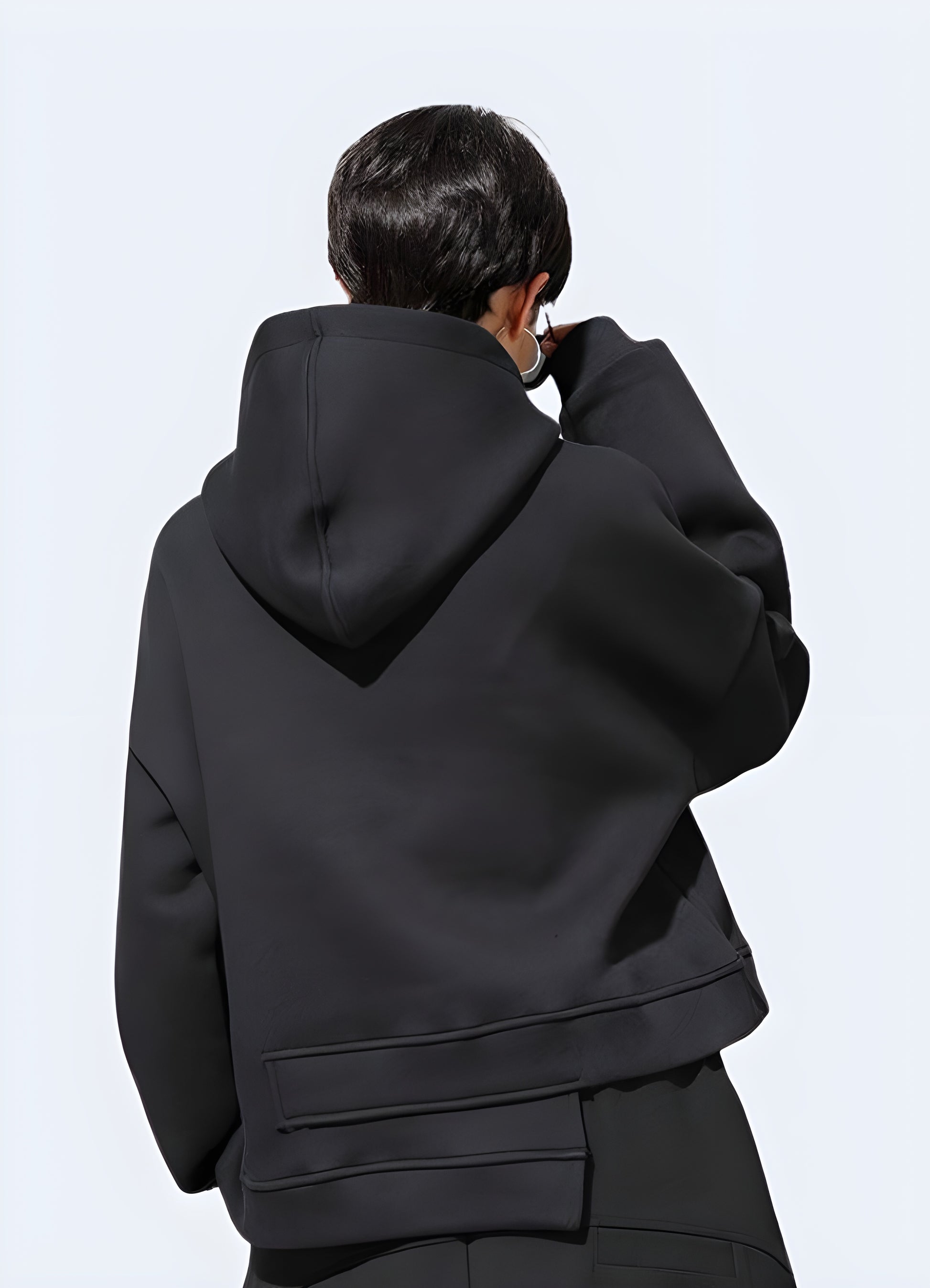 Woman wearing an asymmetrical techwear hoodie, back view, in Canada. Showcasing unique and modern urban style.